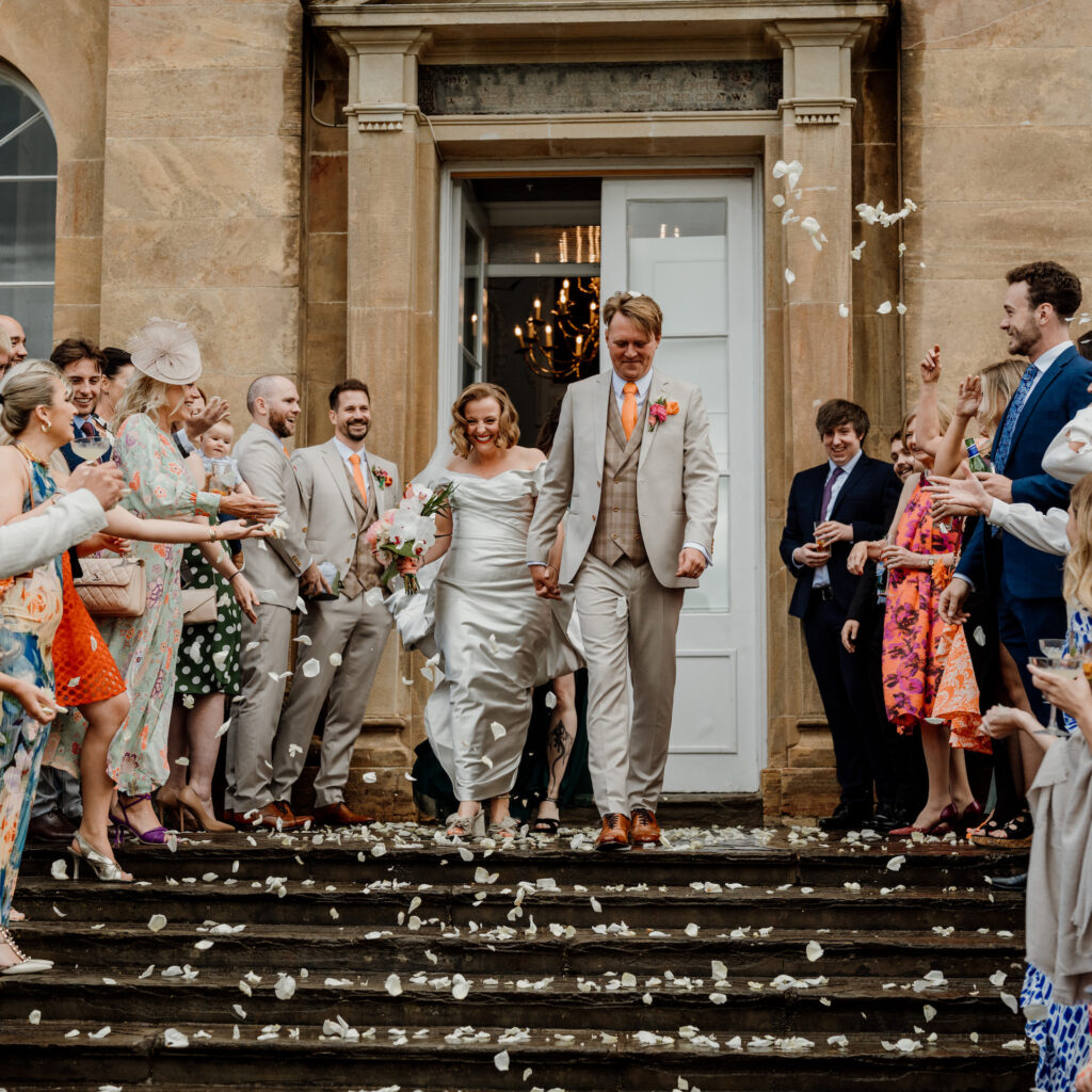 A newly married couple walk down the steps at Kings Weston House.